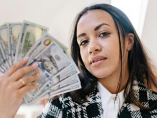 Black woman holding cash, representing funding opportunities for August 2025 grants in New York